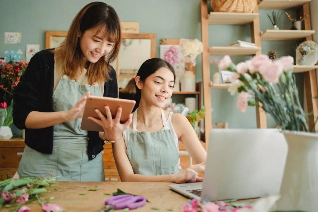 Two florists working with tablet and laptop in shop.