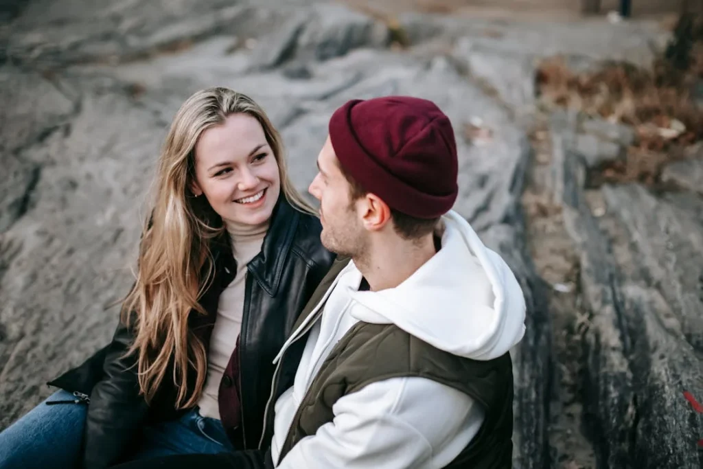 Couple sitting on rocks, smiling at each other.