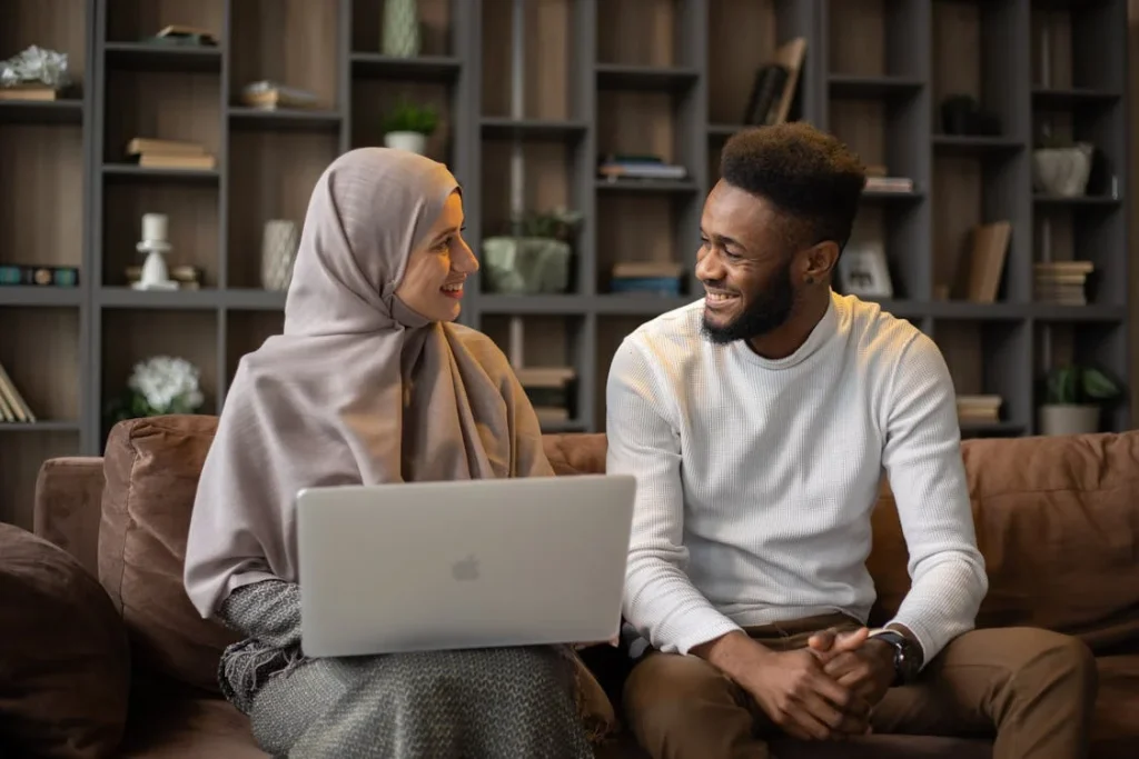 Two people smiling and working on a laptop.
