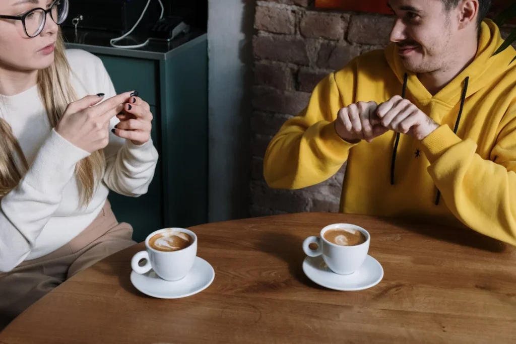 Two people drinking coffee and signing.