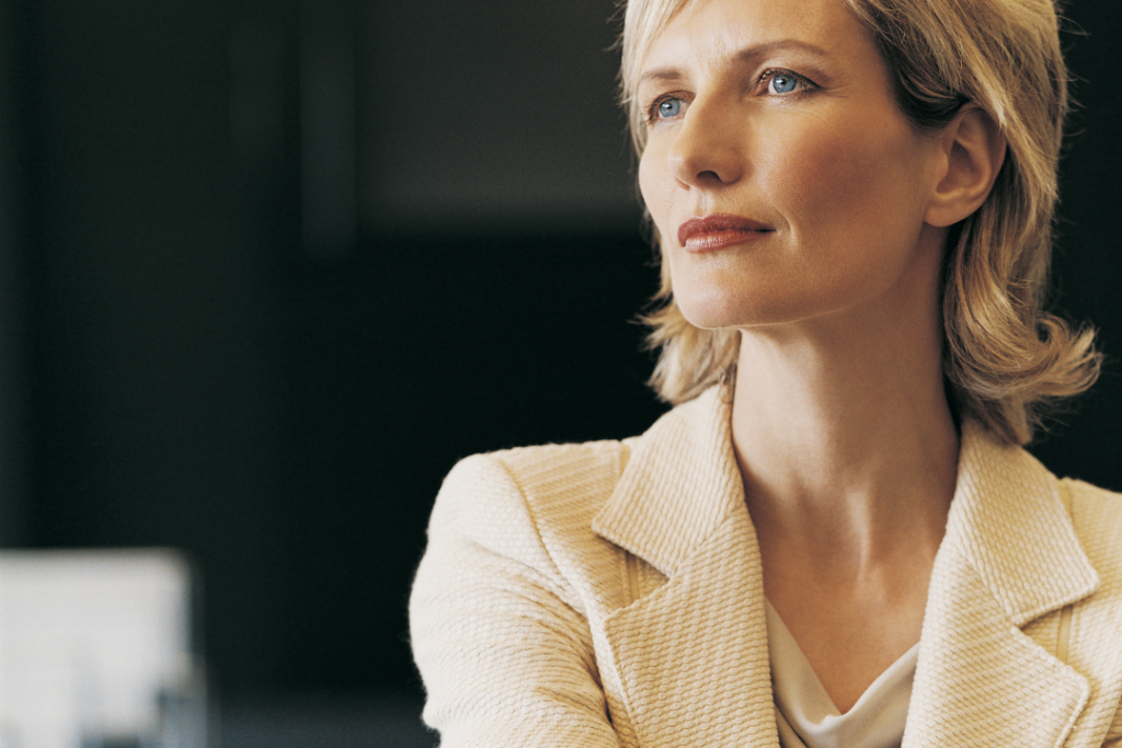 Woman in beige blazer, thoughtful expression