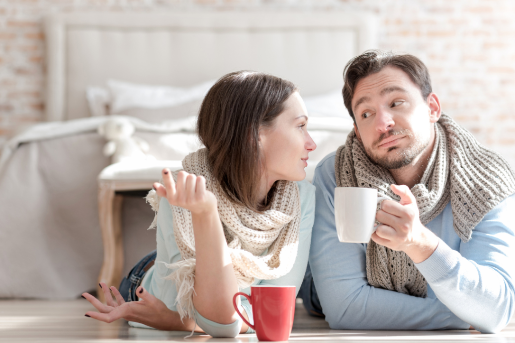 Couple drinking coffee, relaxing in sweaters indoors.