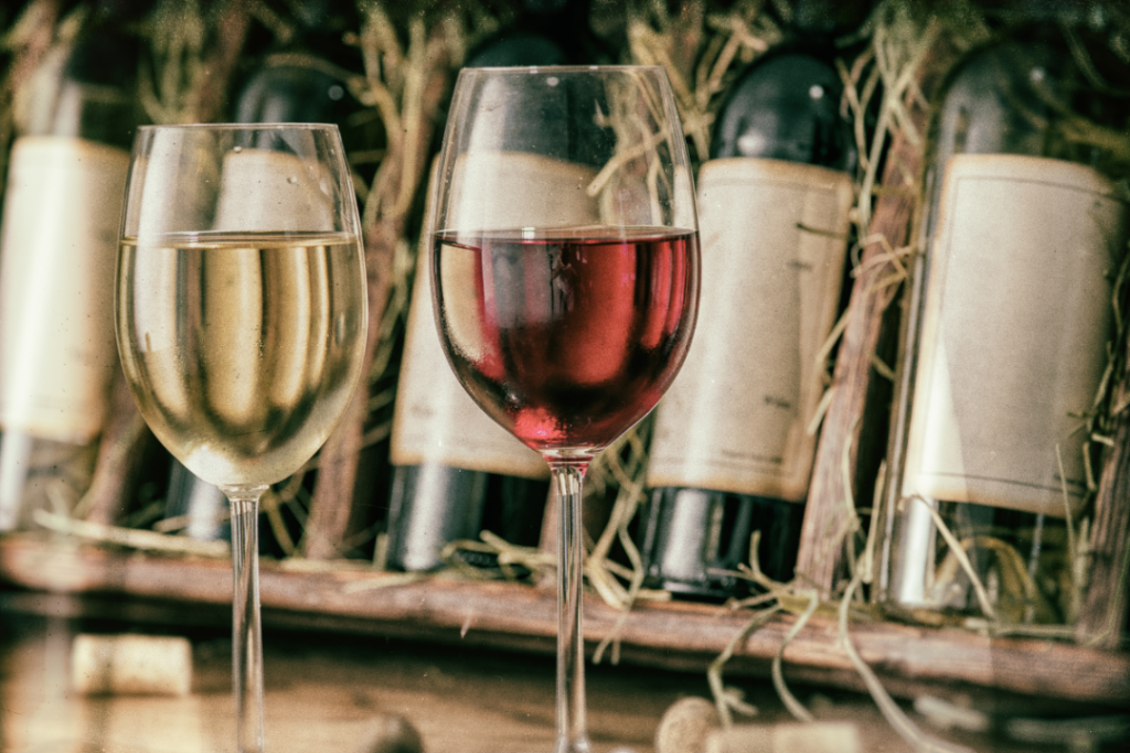 Red and white wine glasses, bottles in background