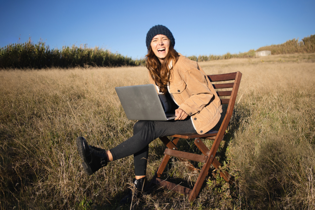 Woman smiling outdoors with laptop on chair