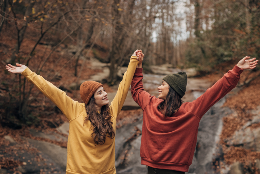 Two friends celebrating in autumn forest.