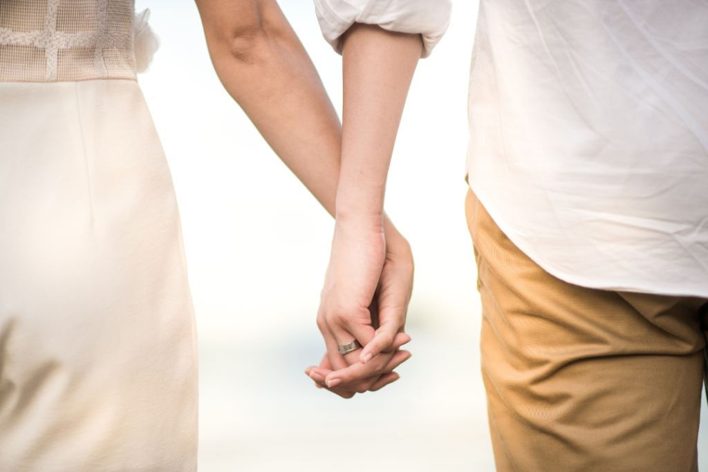 Couple holding hands outdoors, close-up view.