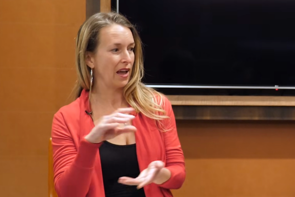 Dina Colada speaking on stage about AI marketing and funnel strategy